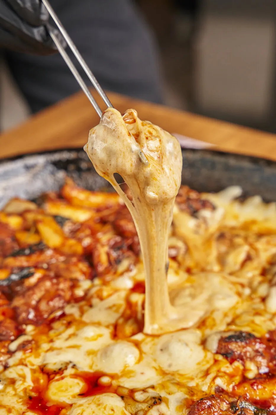 토치로 녹인 모짜렐라 치즈를 닭갈비와 함께 집어 올린 모습