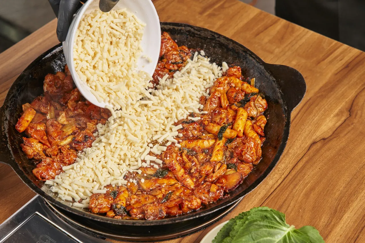 닭갈비를 먹은 뒤 철판에 밥과 치즈를 올려 볶음밥을 만드는 모습